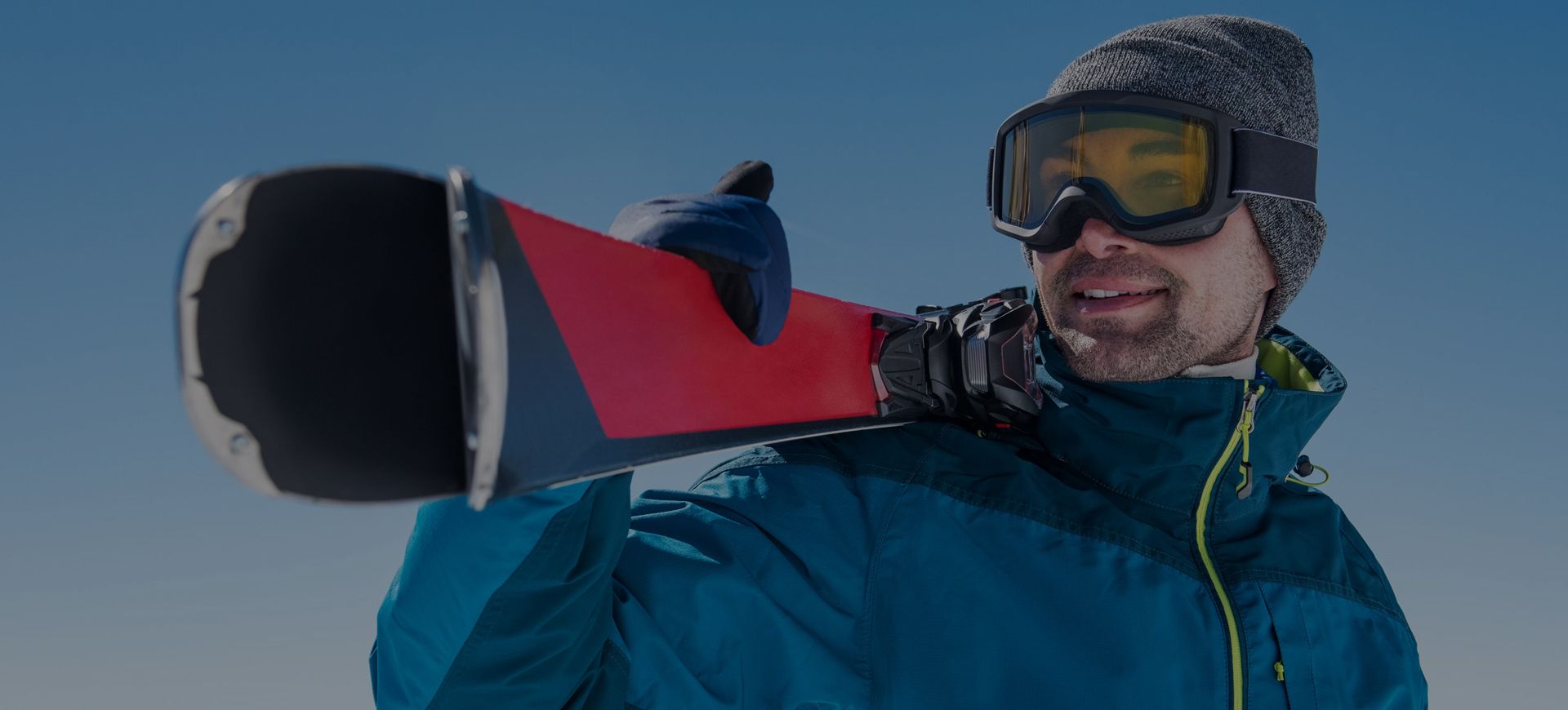 Sciatore felice con sci in spalla noleggiati da Delbono mountain rent